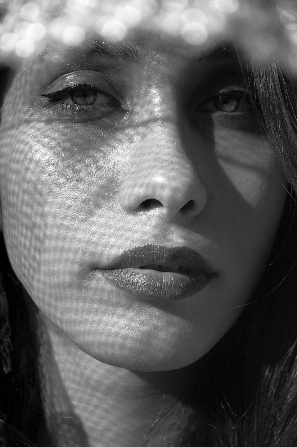 Woman with dark hair posing with geometric shadows on her face.